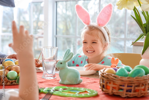 Cute little girl with her family painting Easter egg at home