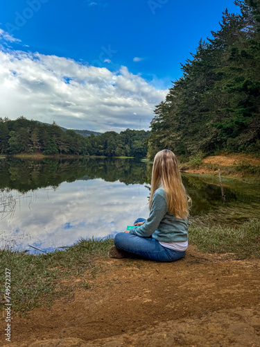 Beautiful blonde woman sitting next to a lake in the forest of Costa Rica