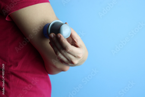 Woman applying a continuos glucose monitoring (CGM) in the arm with a copy spac in the right