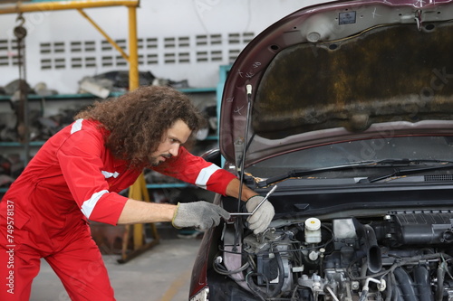 Auto mechanic working in garage. Repair service. Worker mechanics in uniform are working in auto service with lifted vehicle. Car repair maintenance.