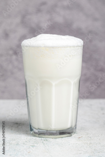 Sparkling buttermilk. Close-up. A glass of ayran on a gray background photo