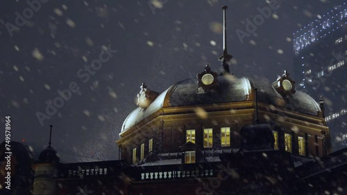 夜の東京に降る雪とライトアップされた東京駅の丸の内駅舎