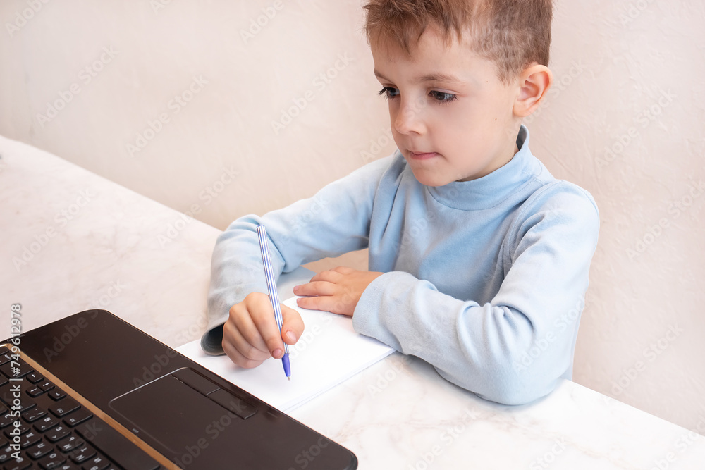 Little boy in a virtual classroom. School at home. little cute boy takes an online lesson. the child studies at home. concept of safe online education Little boy in a virtual classroom. School at home. little cute boy takes an online lesson. the child studies at home. concept of safe online education