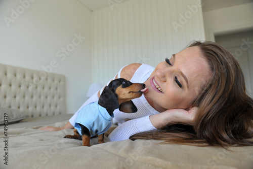 Mulher feliz a vontade em casa com cachorro de estimação filhote fofo de Dachshund  photo