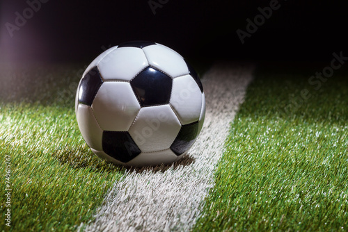 Soccer ball low angle view on white stripe of grass field with dramatic lighting and dark background