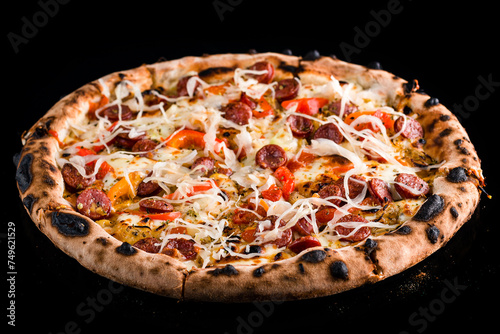 Meat pizza with sausages, sweet peppers, tomatoes, cheese, sauerkraut and spices isolated on black.