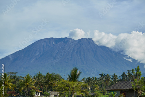 Volcano Agung on the island of Bali emits smoke. Morning view of the volcano over a green rice field on the popular tourist island of Bali.
