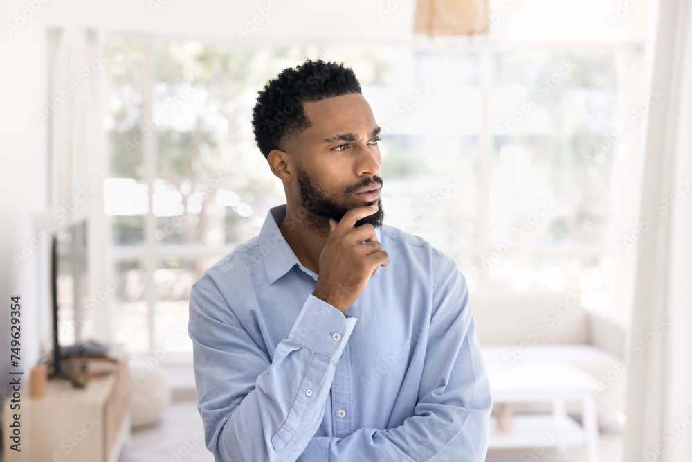 Serious pensive attractive young African man indoor portrait. Thoughtful handsome business professional, entrepreneur, project manager looking away, touching chin, thinking on future ideas Serious pensive attractive young African man indoor portrait. Thoughtful handsome business professional, entrepreneur, project manager looking away, touching chin, thinking on future ideas
