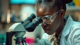 An African American scientist conducting research by peering through a microscope in the laboratory.