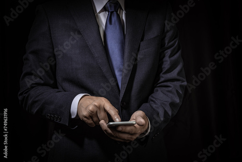黒背景にスマホを操作するビジネスマン photo