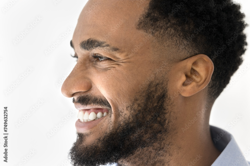 Obraz premium Side view close up portrait of happy young African American man looking forward, smiling, laughing, showing white healthy teeth. Handsome male model promoting beauty care, dental service