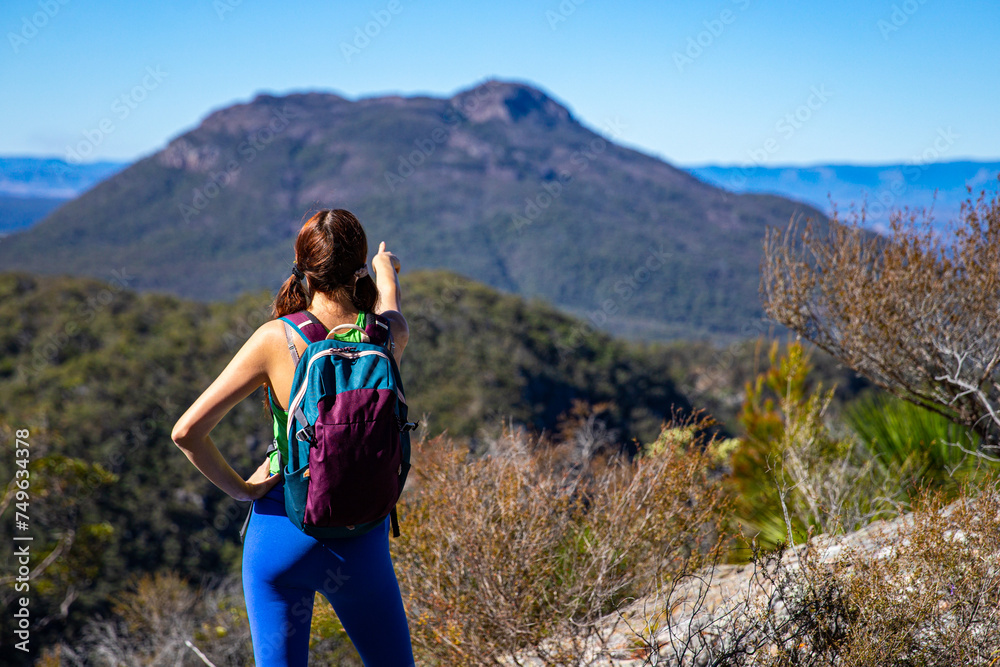 hiker girl looking at the peak of mount maroon from the top of mount may in mount barney national park, south east queensland, australia