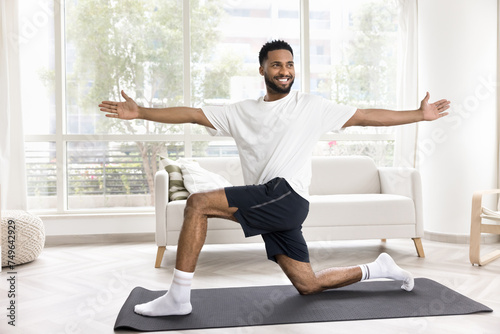 Принти на полотні Happy athletic young African man exercising at home, training body on yoga mat,