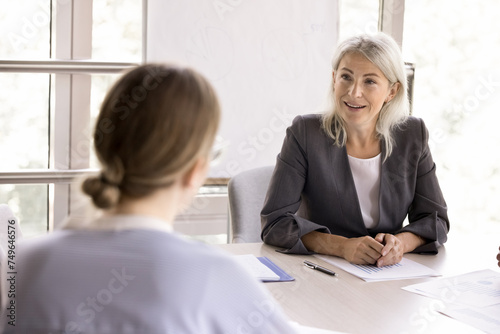 Obraz na płótnie Mature businesswoman negotiates to client during meeting in office, lead training or seminar listen teammate ideas, search solution