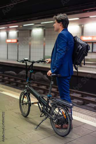 vertical portrait Young Businessman with Electric Bike at Metro Station