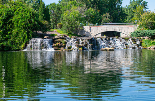 Waterfalls reflected in pond with stone bridge and trees