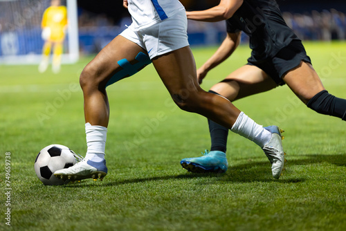 Close up action photo of two soccer players competing in a soccer game. Offensive player trying to score and dribble the ball towards goal.