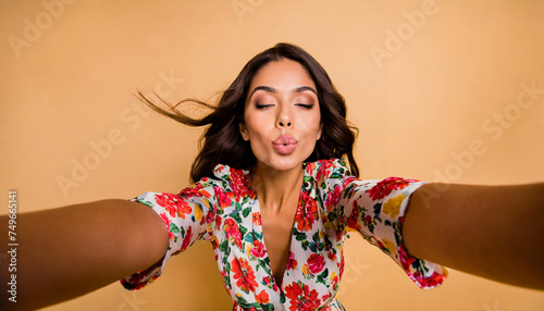 Selfie of flirty sweet lady in flower printed clothes sending a kiss photo