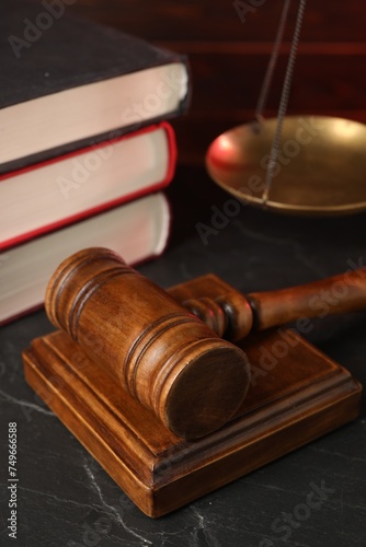 Wooden gavel and stack of books on dark textured table, closeup