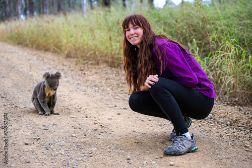 adorable girl sits next to  marsupial koala bear spotted on the road to Mount Maroon in mount barney national park near Brisbane, Queensland, Australia.  Australian native iconic wildlife photo