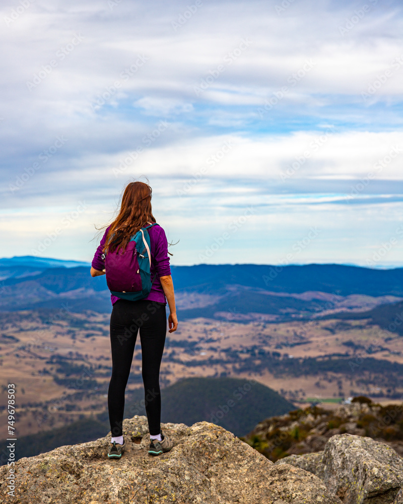 backpacker girl admiring the panorama of mountains in mount barney national park from the summit of mount maroon, queensland, australia