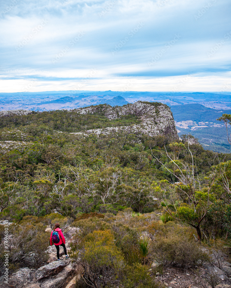 hiker girl walking down steep hil from the summit of mount maroon in mount barney national park, queensland, australia
