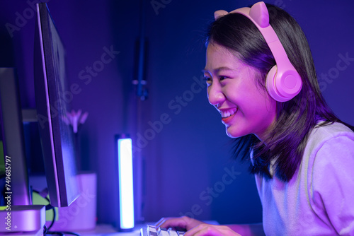 A beautiful female gamer happily plays in a private room with dim lighting that is perfect for creating a gaming mood, She has a passion for playing games, playing games is a hobby.