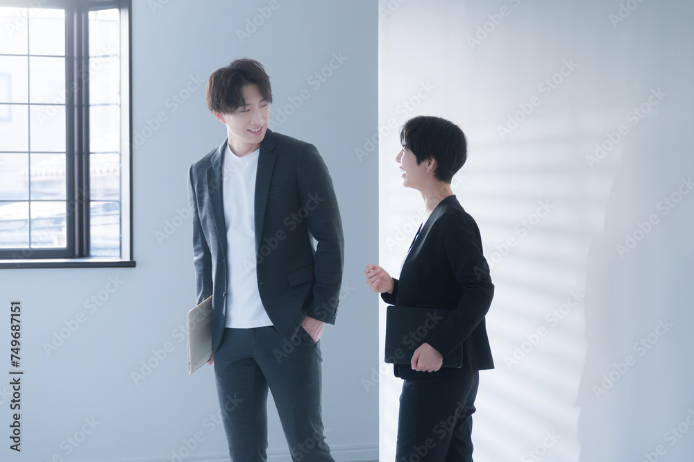 Businessmen and women in suits having meetings and conversations in a stylish office hallway. Businessmen and women in suits having meetings and conversations in a stylish office hallway.