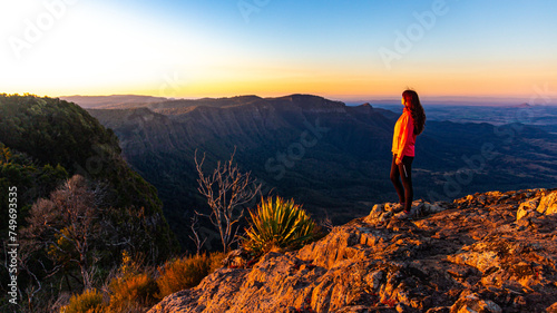 beautiful hiker girl enjoying sunset over unique, folded mountains in south east queensland, australia; main range national park near brisbane, bare rock lookout