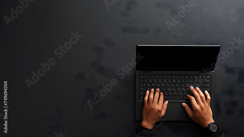 Top view of person typing on a black laptop on a black background