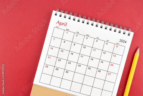 April 2024 desk calendar and pencil on red background.