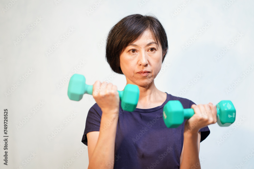 ダンベルでトレーニングする中年女性
