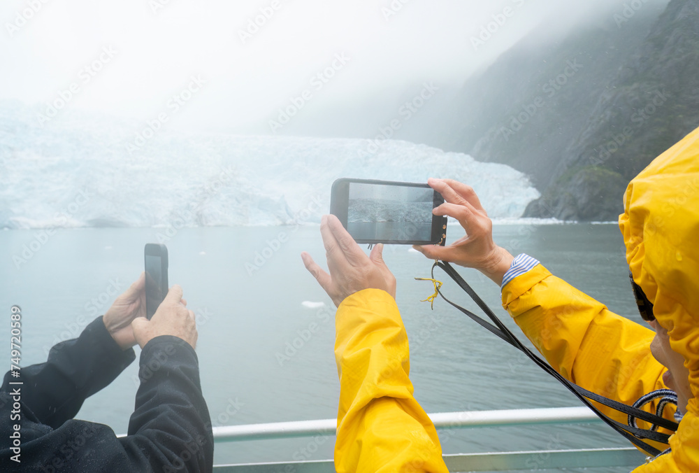 Tourists taking photos of Holgate Glacier using smartphones in the rain. Kenai Fjords National Park. Seward. Alaska.