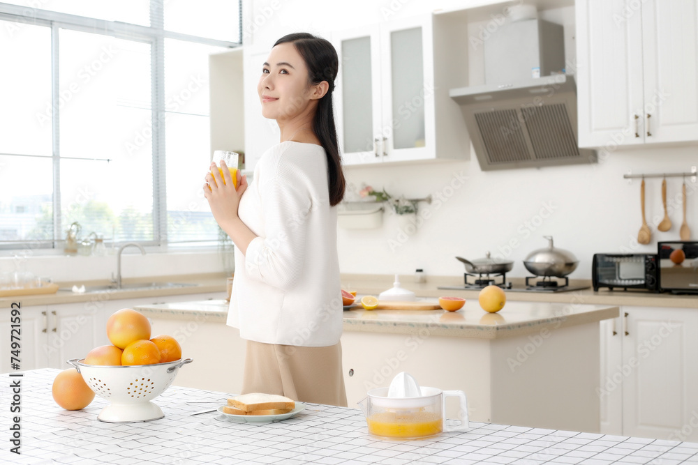 Asian girl drinking juice in kitchen Asian girl drinking juice in kitchen