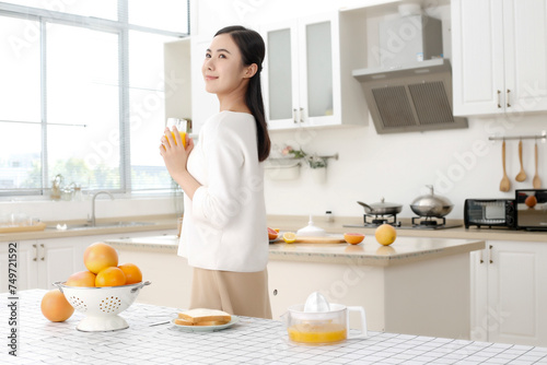 Asian girl drinking juice in kitchen