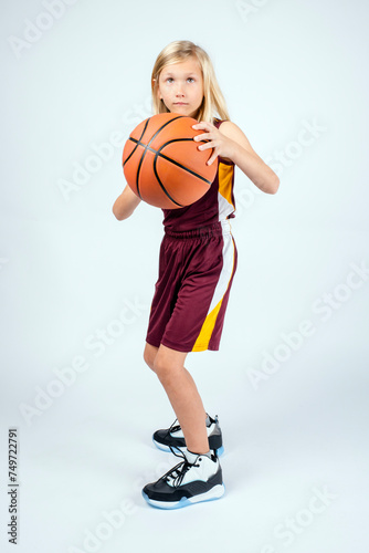 Little blond basketball player with ball in hands looking to pass or shoot