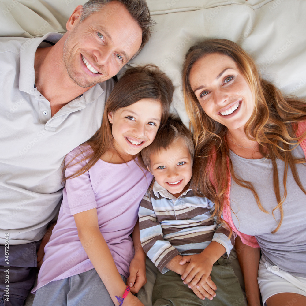 Love, portrait and happy family in bed for relax on holiday, vacation or hotel accommodation on weekend. Face, parents and children with smile, bonding and above in bedroom with healthy relationship Love, portrait and happy family in bed for relax on holiday, vacation or hotel accommodation on weekend. Face, parents and children with smile, bonding and above in bedroom with healthy relationship