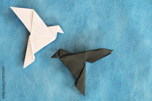 White dove and black rave paper origami in blue background. Good and evil  face fear and opposite attraction concept. 