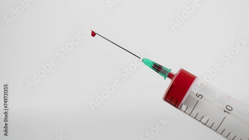 Red drops drip from medical syringe.  Donation campaign syringe drops blood 