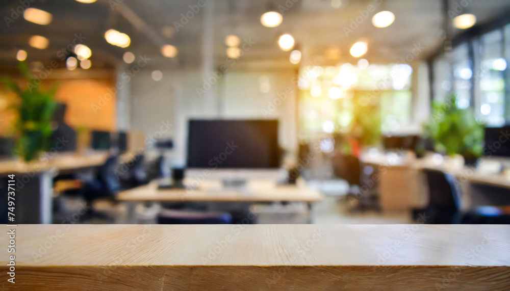 blurred Modern office interior with computers and an empty desk for display in the foreground, large windows, illuminated by natural light. blurred Modern office interior with computers and an empty desk for display in the foreground, large windows, illuminated by natural light.