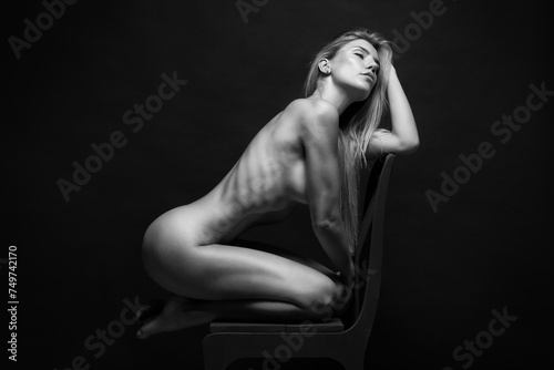 Abstract fine-art portrait. Black and white photo of nude beautiful woman. Female body on black background.	