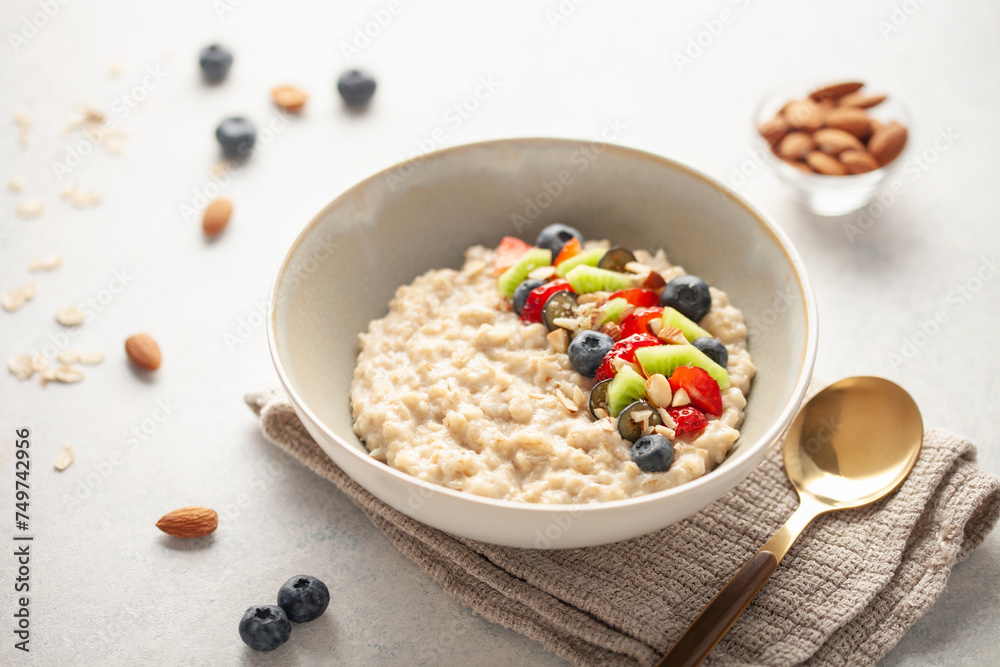 Oatmeal porridge with fruit and berries in bowl on the table. Homemade healthy breakfast cereal with strawberry, kiwi fruits, blueberry and almond Oatmeal porridge with fruit and berries in bowl on the table. Homemade healthy breakfast cereal with strawberry, kiwi fruits, blueberry and almond