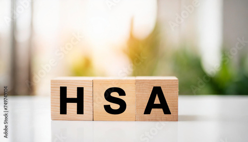 Wooden blocks spell 'HSA' on white table, symbolizing savings, healthcare, and investment in clean, minimalist setting