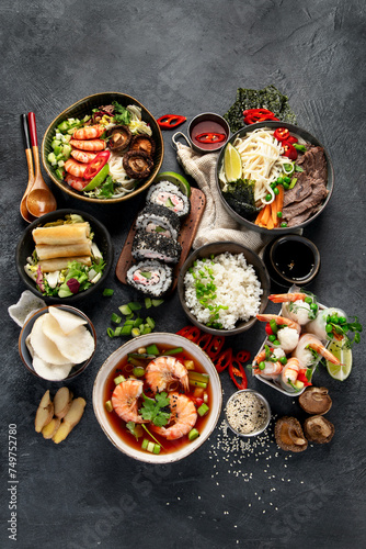 Traditional Asian food table. Spring roll, rice, shrimp, sushi, vegetables, meat on dark background