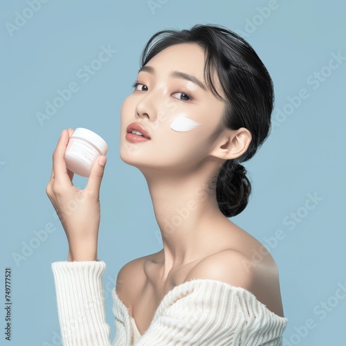 Asian beautiful woman with perfect skin holds cosmetic cream. Female beauty concept