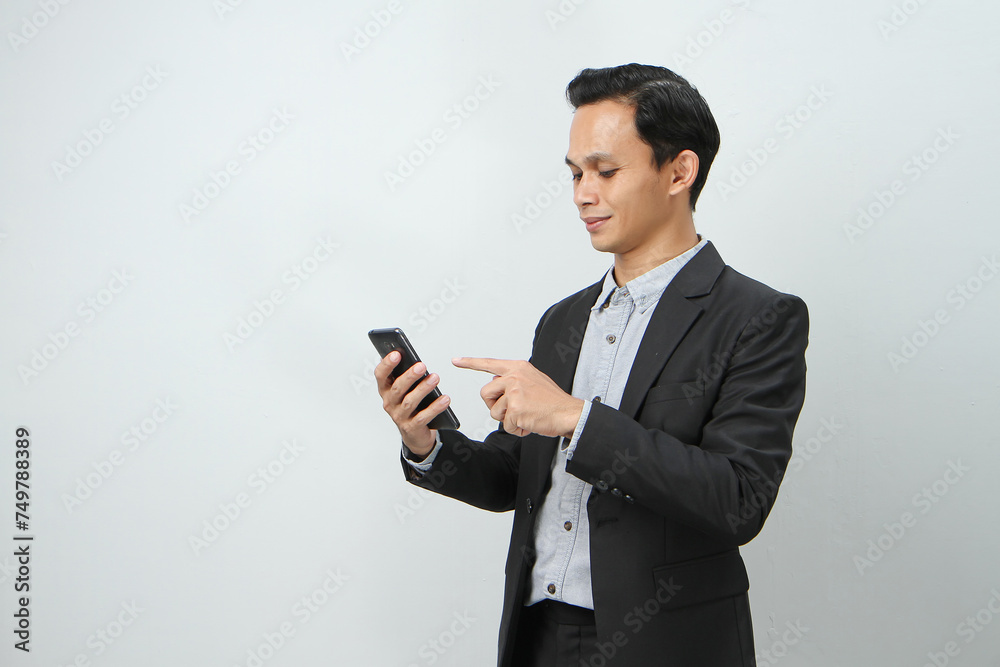 happy asian indonesian business man in suit holding smart phone on isolated background happy asian indonesian business man in suit holding smart phone on isolated background