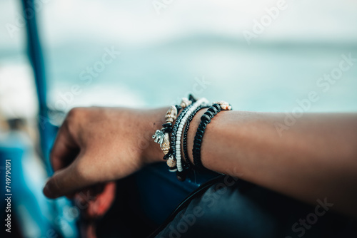 Hands and nautical bracelets placed on the chairs of a sailing ship.