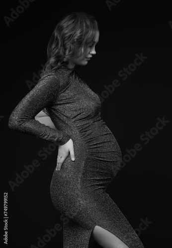 Black and white portrait of young pregnant female in grey sequin dress.