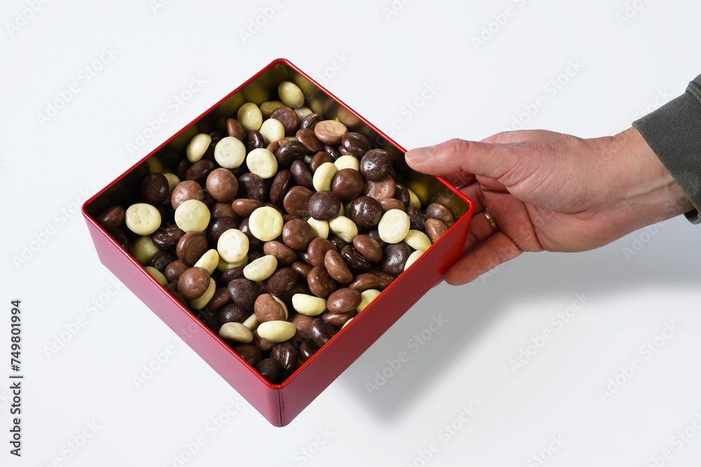 Hand offers square cookie tin with chocolate cookies. Studio shot subject is made isolated on white background Hand offers square cookie tin with chocolate cookies. Studio shot subject is made isolated on white background