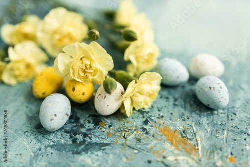 Photography Yellow beautiful flowers and blue and yellow colored easter eggs on a blue picturesque oil painting background close up